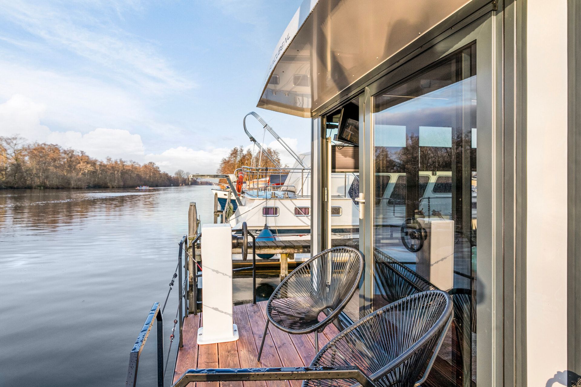 Terras van een woonboot aan het water in Kortenhoef bij laag zonlicht